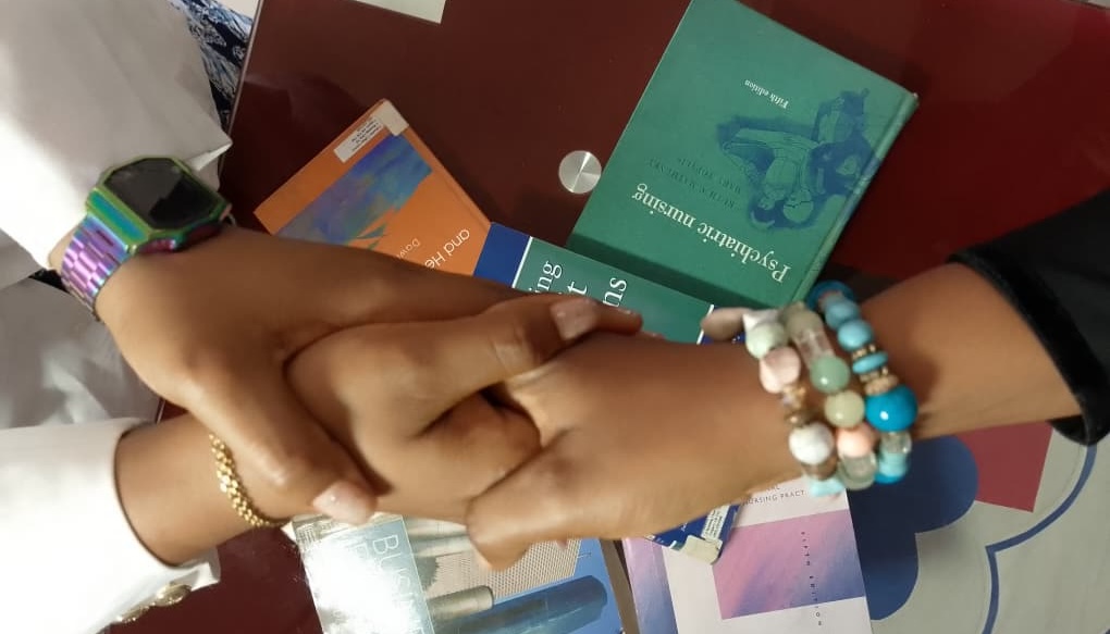 Two people clasping hands over a table of health booklets